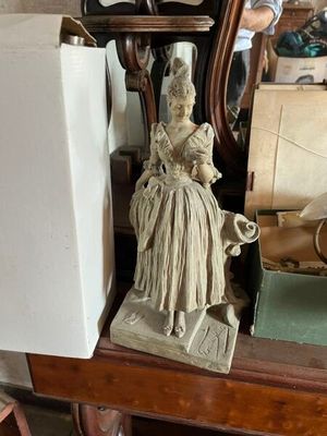 une statue de femme assise sur une table à côté d'une horloge
