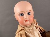 an old doll with blue eyes and a gold dress holding a fan
