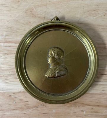 an antique brass plate with a portrait of a man on it