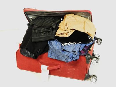 une valise rouge remplie de vêtements et un sac noir