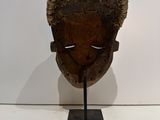 an image of a wooden mask on a stand on a white surface
