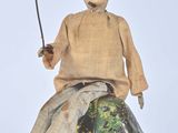 a small doll sitting on top of a rock with a sword