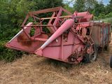 un tracteur garé dans l'herbe près d'une moissonneuse-batteuse rose