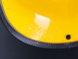 a close up of a yellow helmet on a black surface