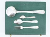 a silver spoon, fork, and spoon rest on a green surface
