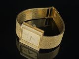 an image of a gold watch on a black surface with a reflection