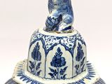 a blue and white vase with a bear on top