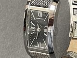 a silver watch with a black face on a black surface