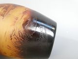 un vase brun et noir posé sur une surface blanche
