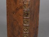 an old book with a brown cover sitting on top of a table