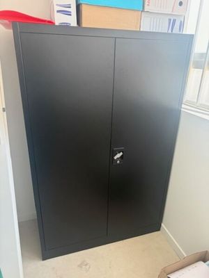 une armoire noire dans un coin de la pièce, près d'une fenêtre