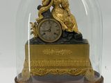 a gold clock under a glass dome on a table