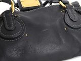 black leather handbag with gold hardware on a white background