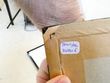 une personne tenant une boîte marron sur laquelle est collé un autocollant