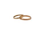 two gold wedding rings sitting side by side on a white background