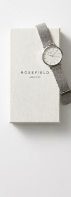 a white watch sitting on top of a book with a silver band