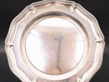 a silver plate on a stand on a black surface
