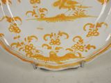a yellow and white plate with a bird and flowers on it