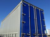 the back of a semi truck with a blue trailer parked in a parking lot