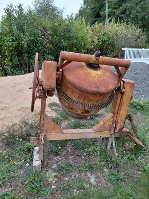 a cement mixer that is sitting in the grass