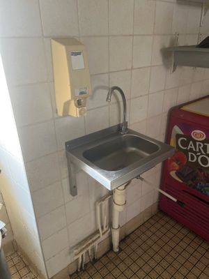 un évier et un distributeur de boissons gazeuses dans une petite pièce