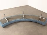a curved glass shelf on the floor next to a wall