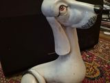 une statue de chien blanc assis par terre à côté d'un ordinateur portable