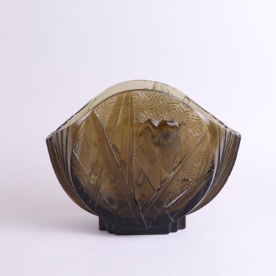 un vase en verre orné d'un oiseau, posé sur une surface blanche