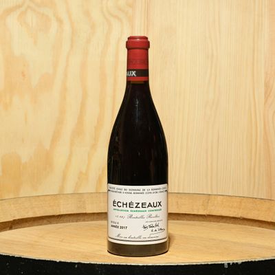 a bottle of wine sitting on top of a barrel