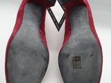 a pair of red sued shoes with black soles on a white surface