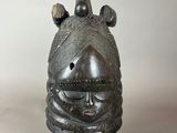 a close up of a metal mask on a black stand