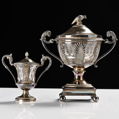 two silver vases sitting on top of a table next to each other