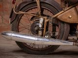 a old motorcycle parked in a garage with a brick wall in the background