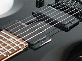 a close up of a black electric guitar on a white surface
