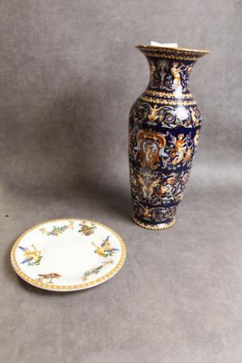 a blue and gold vase next to a small plate