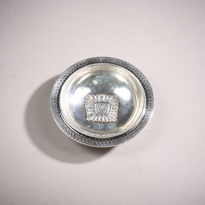 un petit plat en argent avec un couvercle en argent posé sur une table