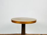 une table ronde en bois avec un piètement en métal, posée sur un parquet
