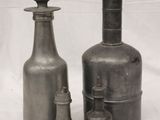 three bottles and a vase sitting on a white surface