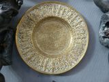 a gold plate sitting on a table next to other items