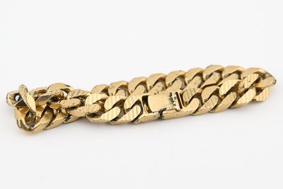 gros plan d'un bracelet en or sur fond blanc