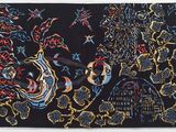 un gros plan d'un tableau posé sur une surface noire, avec un bâtiment en arrière-plan
