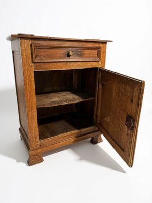 une petite armoire en bois dont la porte est ouverte, sur fond blanc
