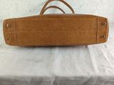 tan leather handbag on a bed with a white sheet