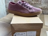 purple shoes on top of a cardboard box in front of a brick wall