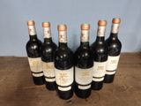 six bottles of wine are lined up on a wooden table