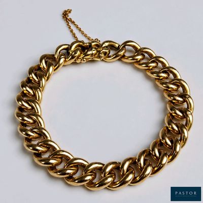 gros plan d'un bracelet en chaîne en or sur une surface blanche