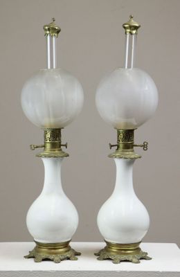 une paire de lampes en verre blanc avec des pieds en laiton, posées sur une surface blanche