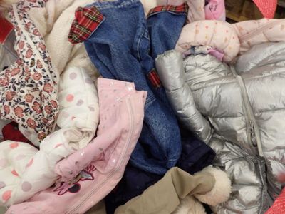 un tas de vêtements et un ours en peluche dans un panier