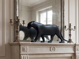 une statue de chat posée sur une cheminée, devant un miroir