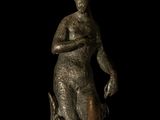 bronze statue of a woman with a dog on a black background